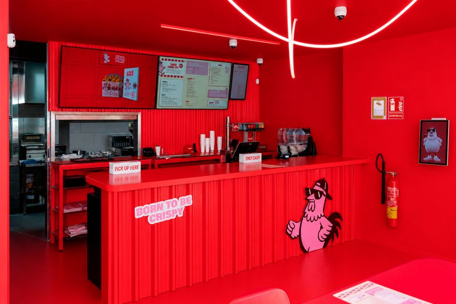 Mostrador rojo de Crispins con neones en el techo y pantallas de carta